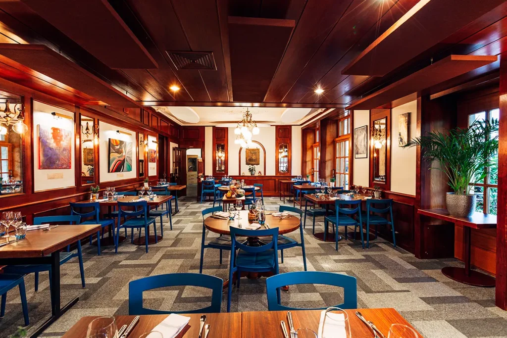 Photographie d'architecture intérieure réalisée par Speetch : salle de restaurant élégante avec boiseries raffinées et mobilier design bleu, shooting immobilier de prestige dans le Canton de Vaud.