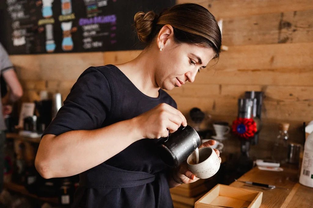 Photographie de reportage en entreprise par Speetch au café Sleepy Bear à Lausanne : portrait d'une barista en pleine préparation d'un café, illustration du savoir-faire artisanal dans le Canton de Vaud.