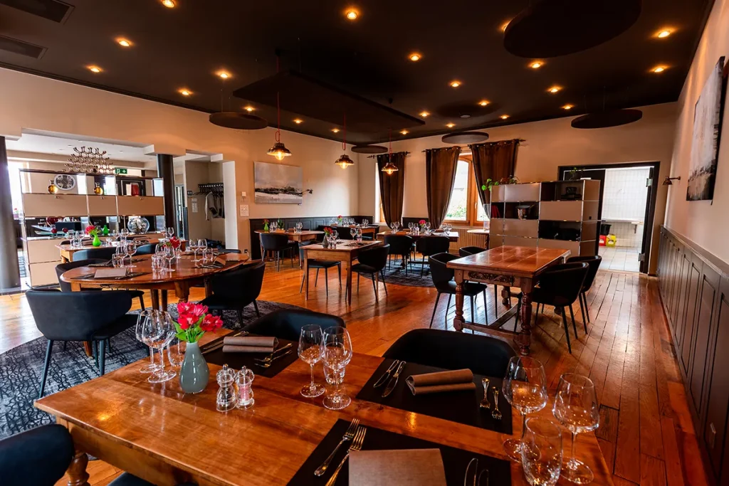 Photographie d'architecture intérieure par Speetch : salle de restaurant élégante avec mobilier en bois et éclairage chaleureux, shooting professionnel pour l'immobilier et le commerce dans le Canton de Vaud.